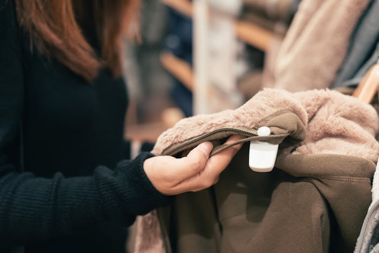 Close-up of a woman examining a coat in a clothing store, focused on texture and design.