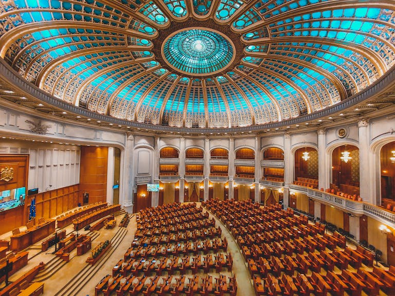 Vibrant interior of a parliament hall with a grand dome and intricate architecture.