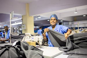 A cheerful worker processes fabric in a bustling textile factory.
