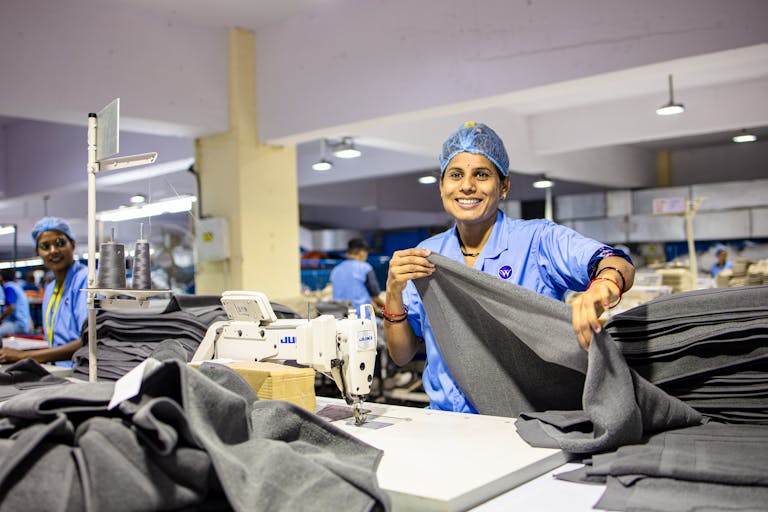 A cheerful worker processes fabric in a bustling textile factory.