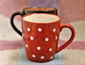Close-up of a red polka dot mug set on a rustic fabric background, perfect for cozy themes.